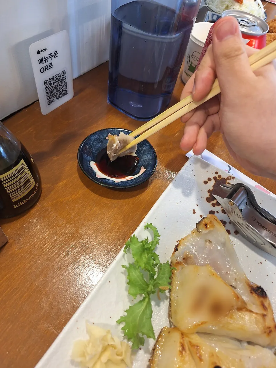 A piece of grilled black cod pulled apart with chopsticks
