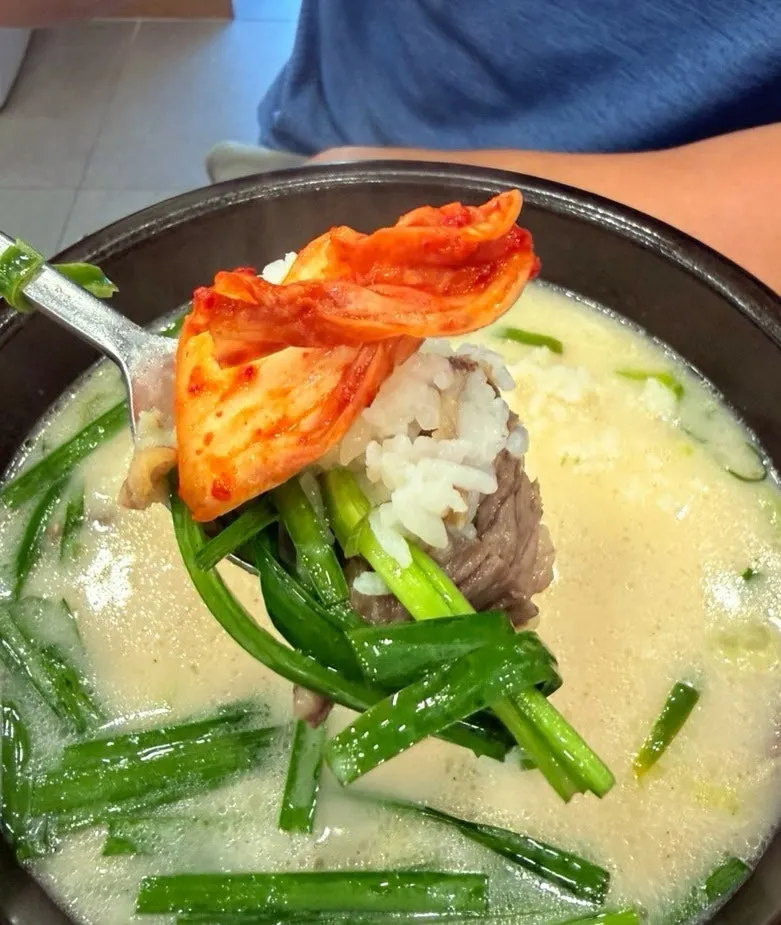 A spoonful of seolleongtang topped with geotjeori kimchi