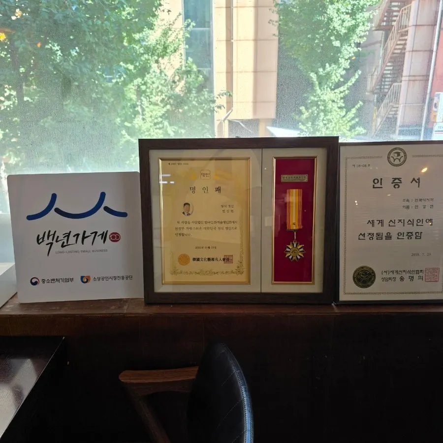 Photos and certificates hanging on the wall at Min Cook Dasima