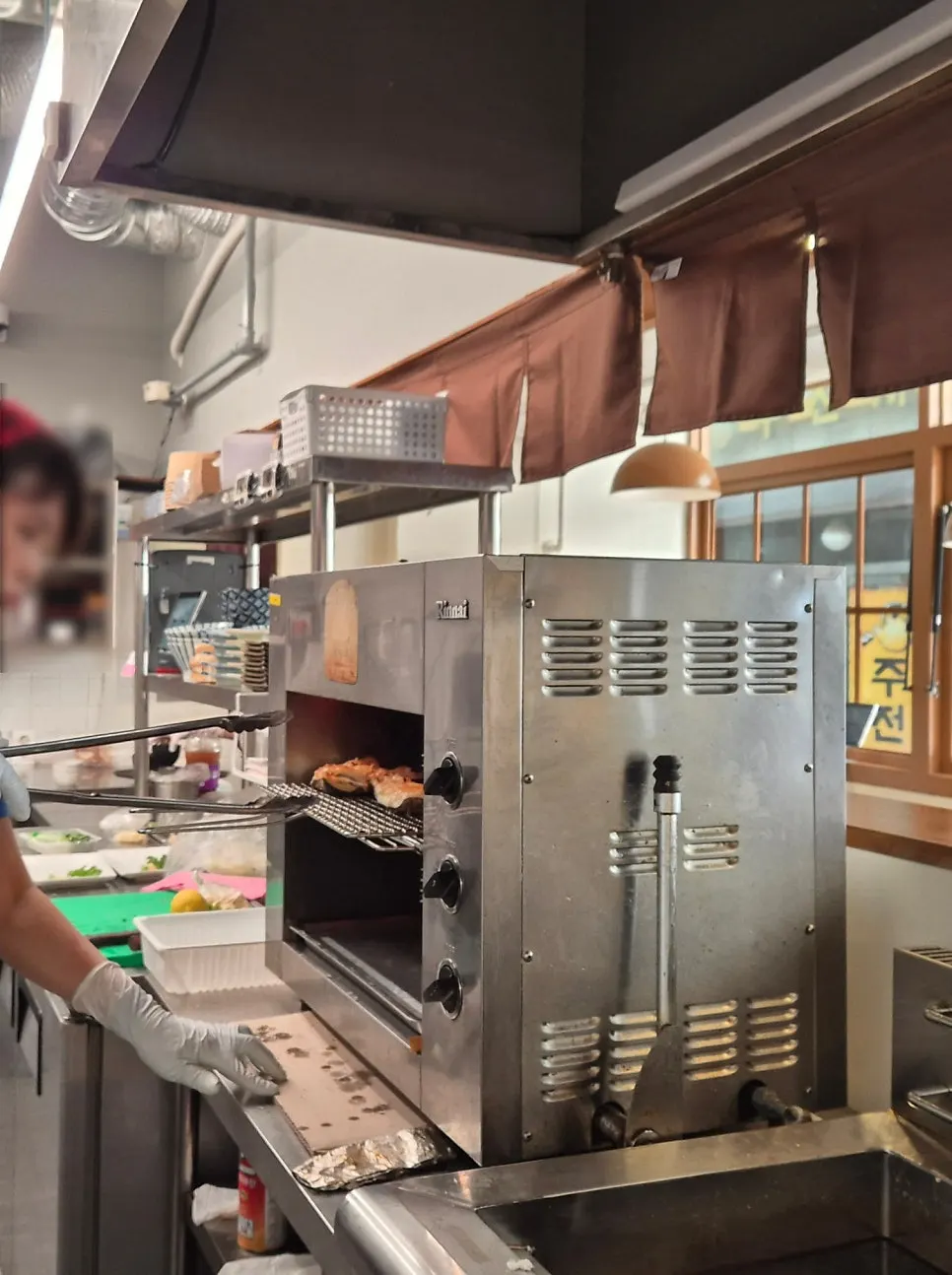 Kitchen grilling fish under a large ventilation hood