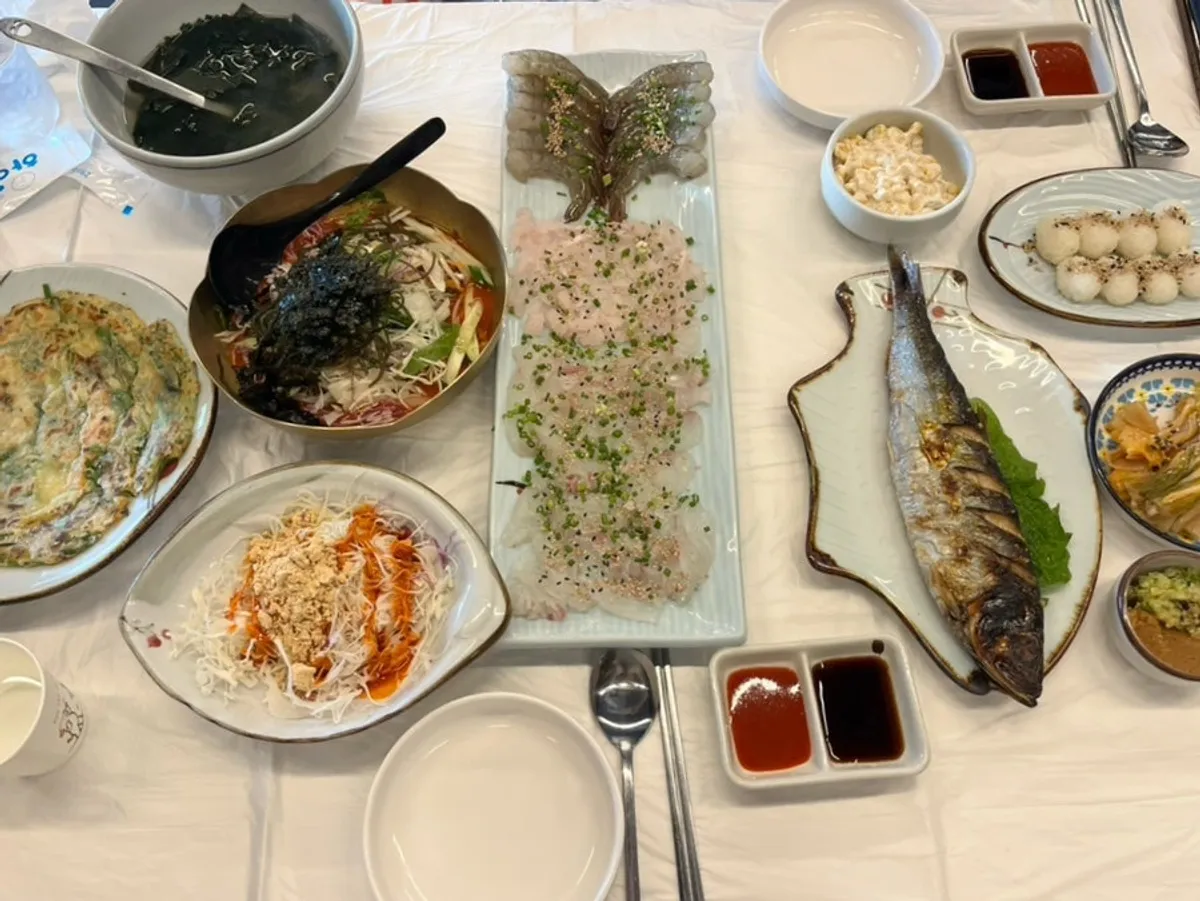 Table spread of raw shrimp and live fish sashimi