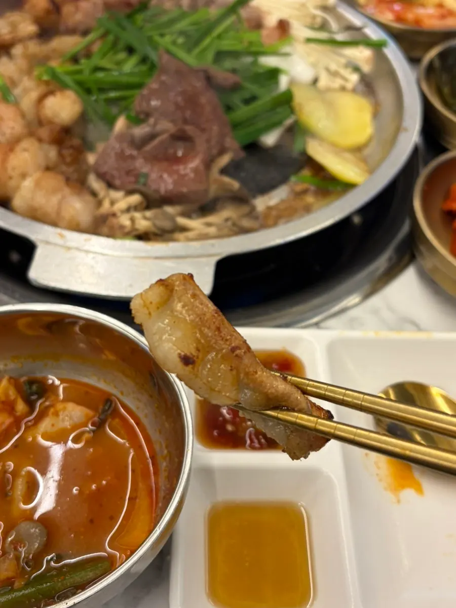 A bite of gopchang wrapped in mountain garlic leaf
