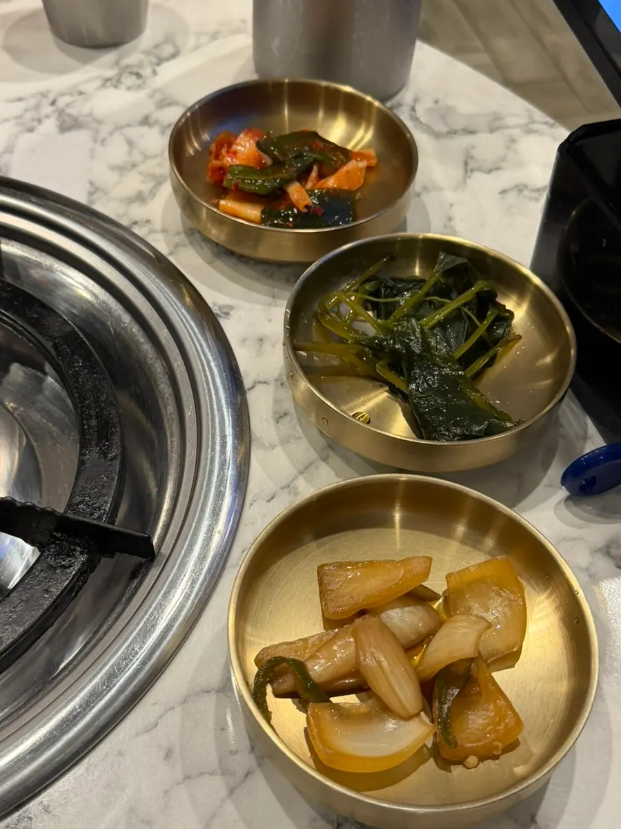 Side dishes of scallion kimchi, wild garlic leaves, and pickled onions