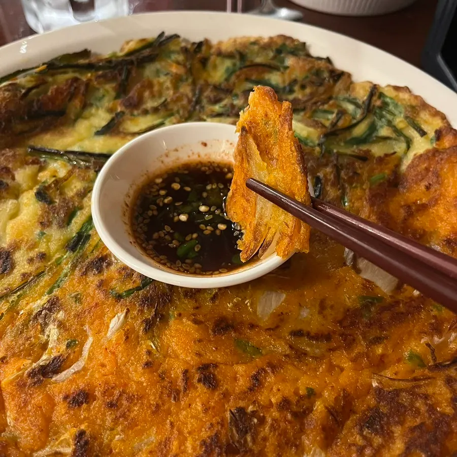 A piece of jeon dipped in soy sauce