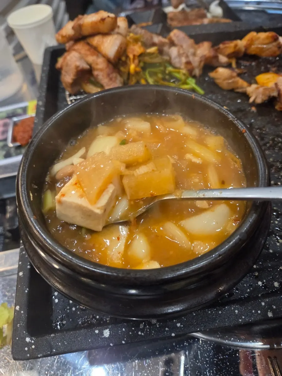 Table spread of meat and side dishes on the grill plate at Hwapyeongjip