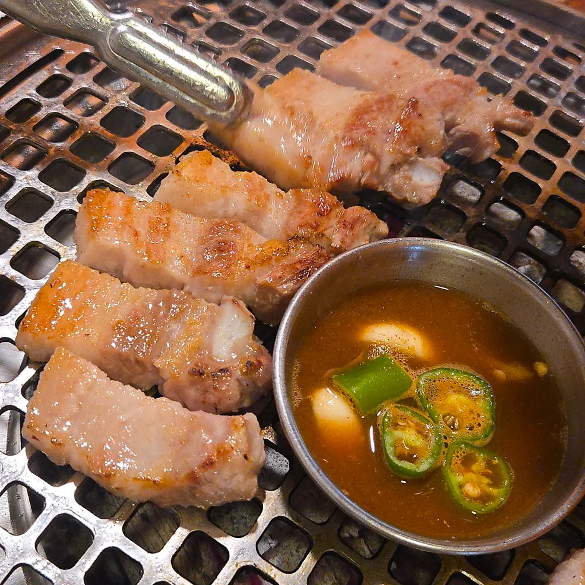 Thick pork belly grilling over charcoal