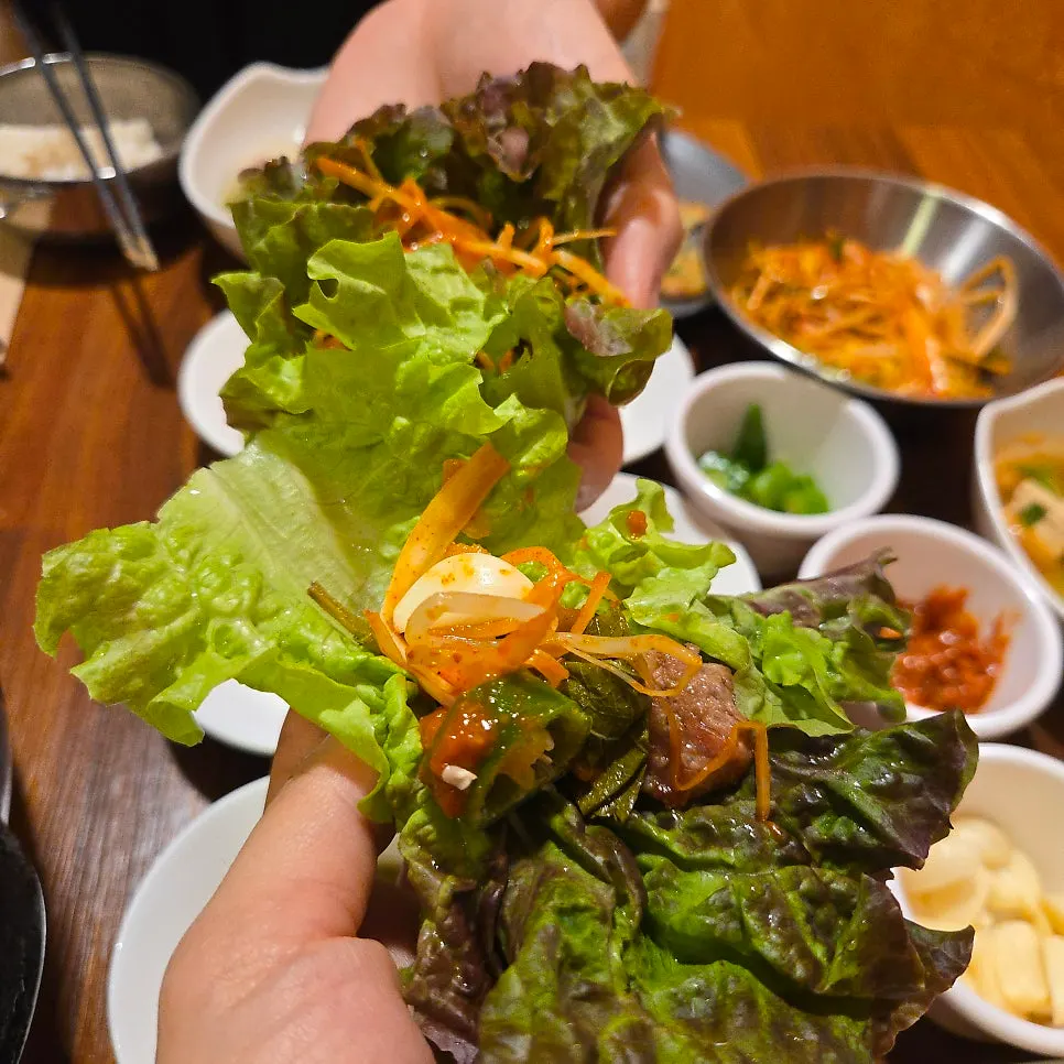 A wrapped bite of pork belly with lettuce