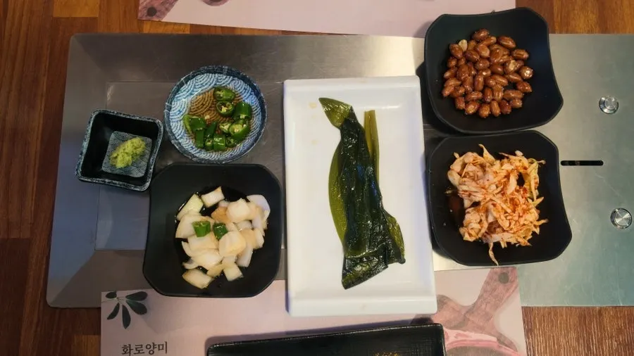 Banchan spread of onion, chili, kimchi varieties, and wasabi