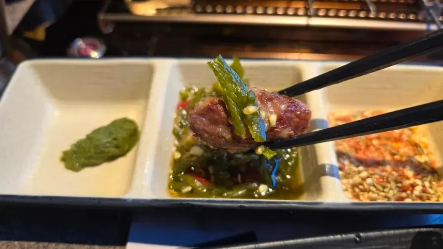 A piece of lamb skewer topped with chili sauce