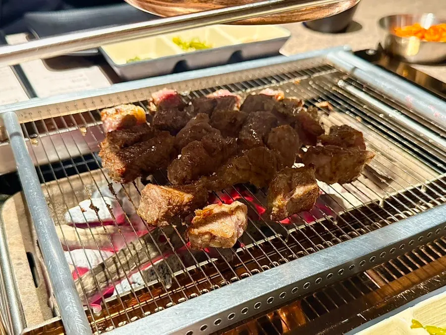 Staff member grilling the lamb chops over charcoal