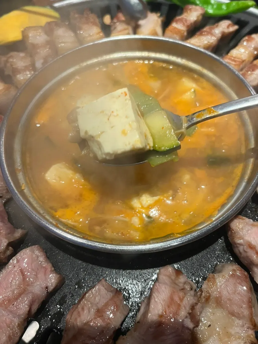 Deep pot of doenjang stew full of tofu and vegetables