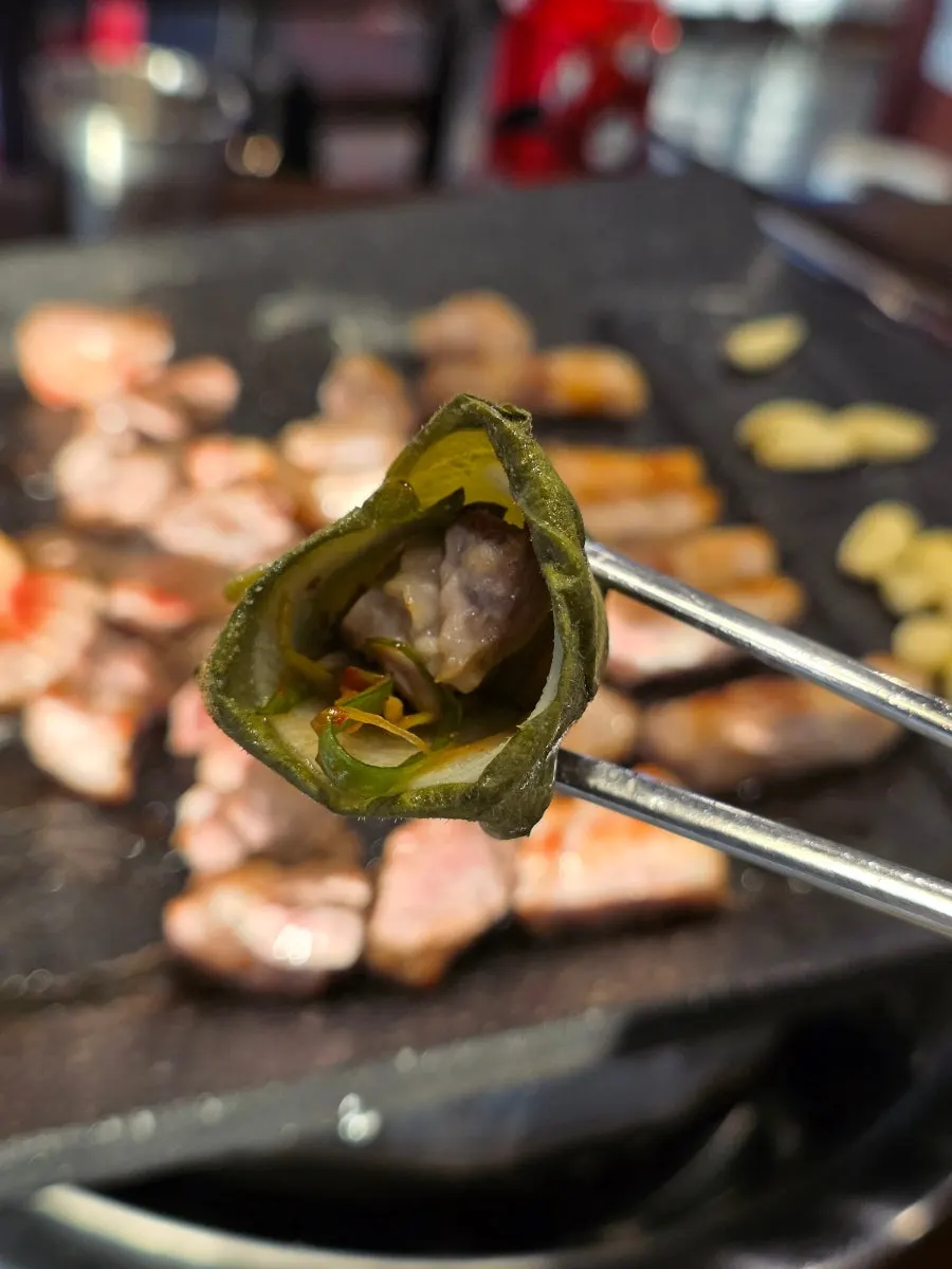A piece of oak-fired grilled meat picked up with chopsticks