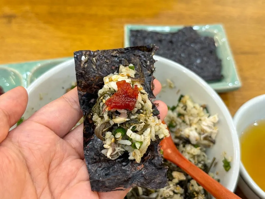 A bite of gim topped with pickled burdock root