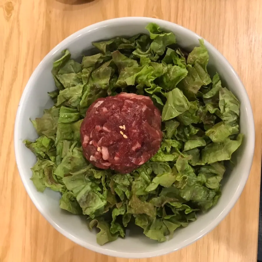 Yukhoe bibimbap topped with lettuce and fresh raw beef