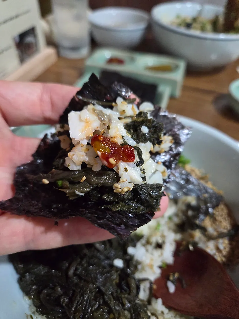A bite of gopchang gim wrapped with bibim jeotgal