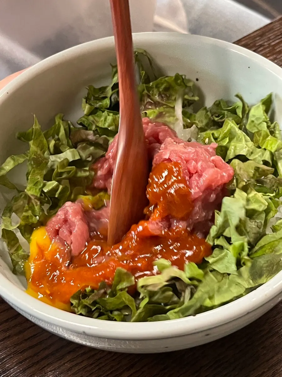 Vivid red yukhoe and egg yolk topping the bibimbap