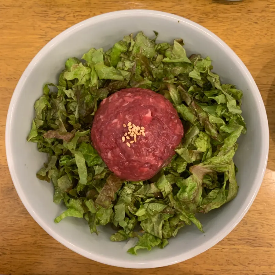 A bowl of yukhoe bibimbap piled high with lettuce