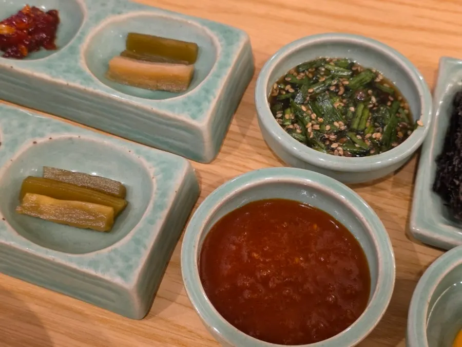 Table setting with side dishes, sauce, gochujang, and egg yolk