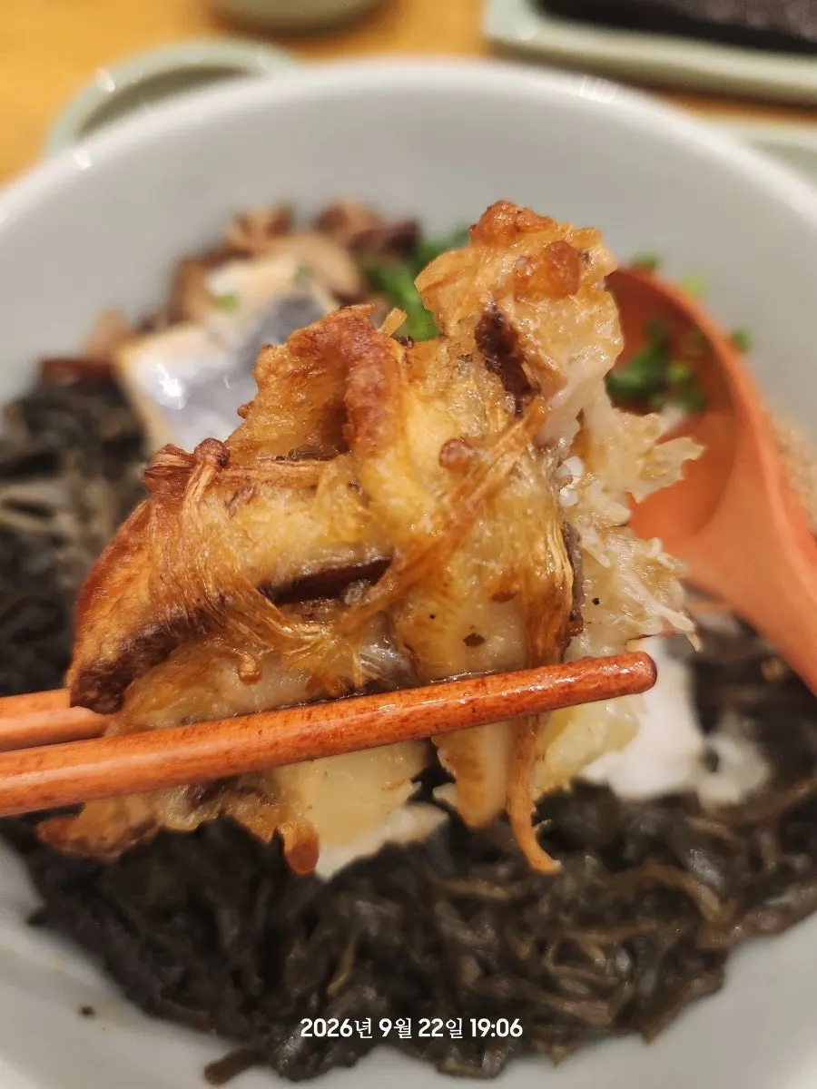 A piece of mushroom pancake picked up with chopsticks