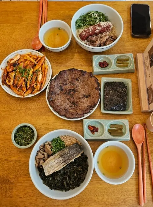Side dishes including pickled gungchae, bibim jeotgal, and soy-broth soup