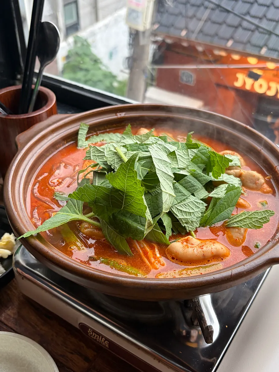 Earthenware pot of gopchang stew piled with perilla leaves