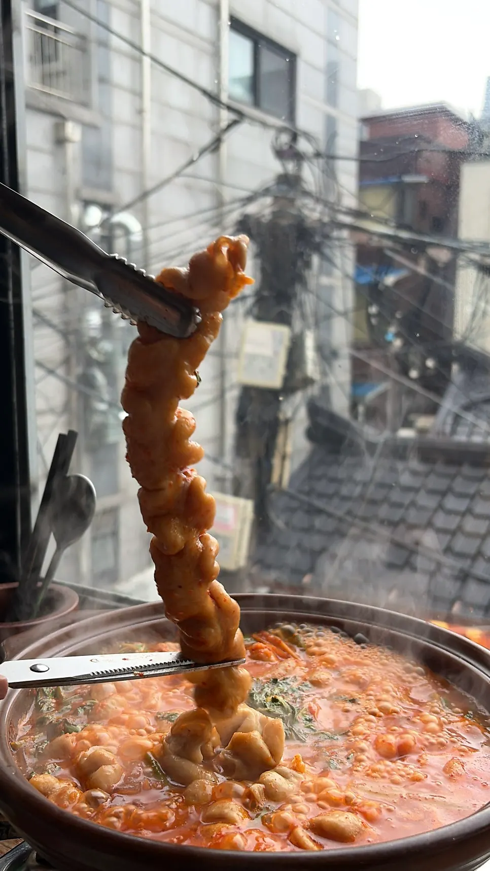 Gopchang stew bubbling as the perilla leaves wilt down