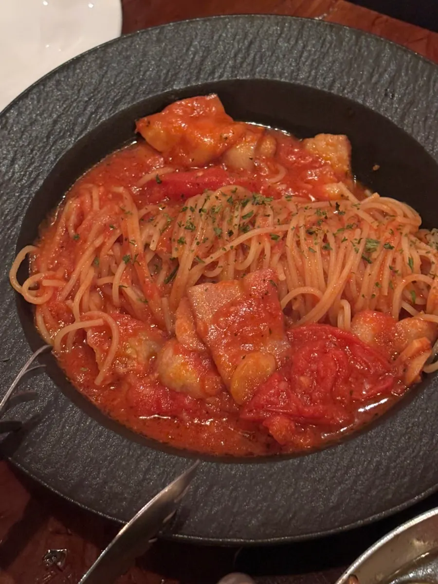 Tomato pasta topped with large bacon pieces
