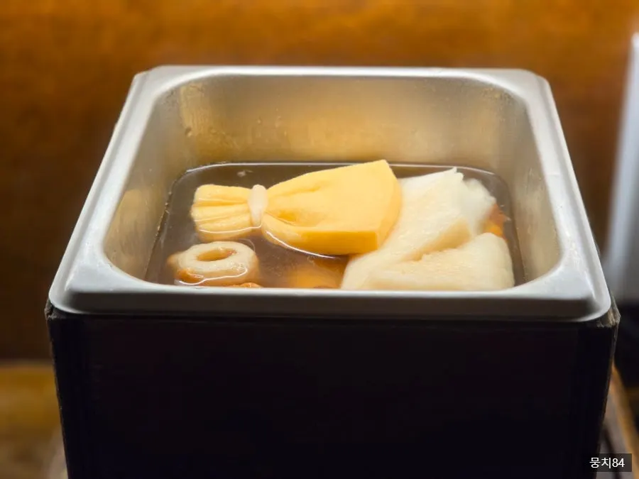 Oden pieces added one at a time into the simmering broth