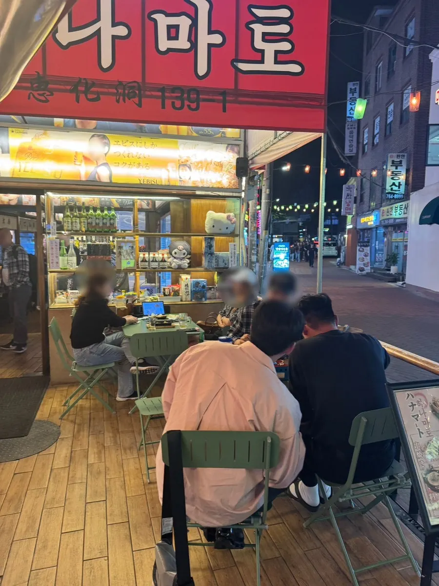 Outdoor tables under Japanese-lettered signage and lighting