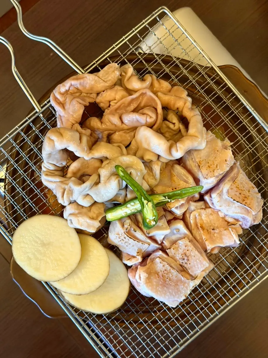 Rice cake gopchang stew topped with straw-fire seared whole gopchang and grilled chicken