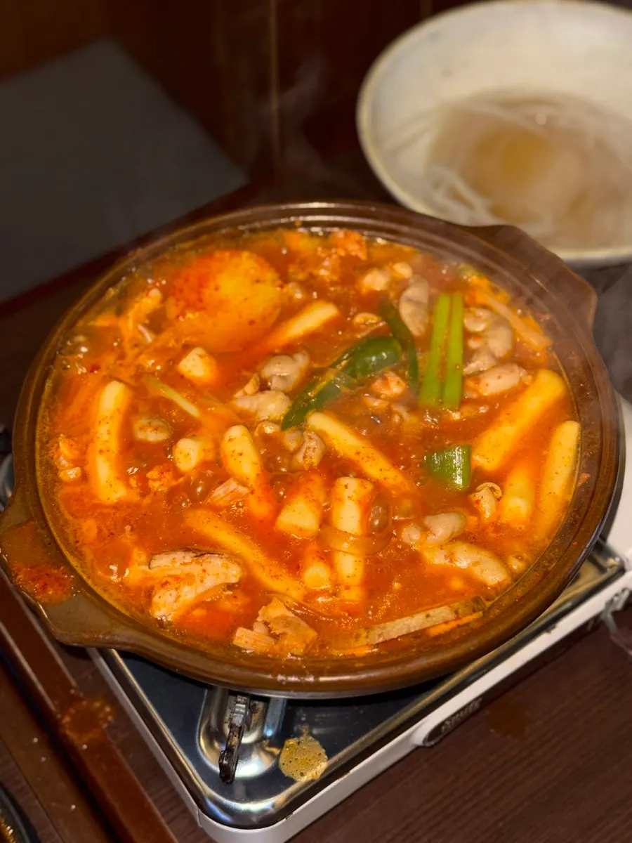 Full shot of the red broth boiling in the rice cake gopchang stew