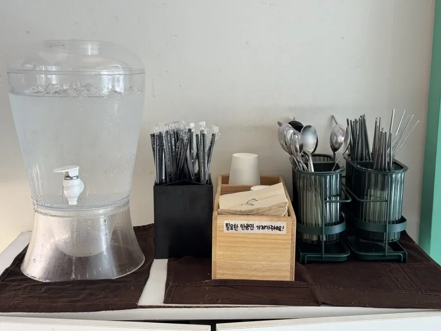 Self-service bar with utensils, napkins, and water