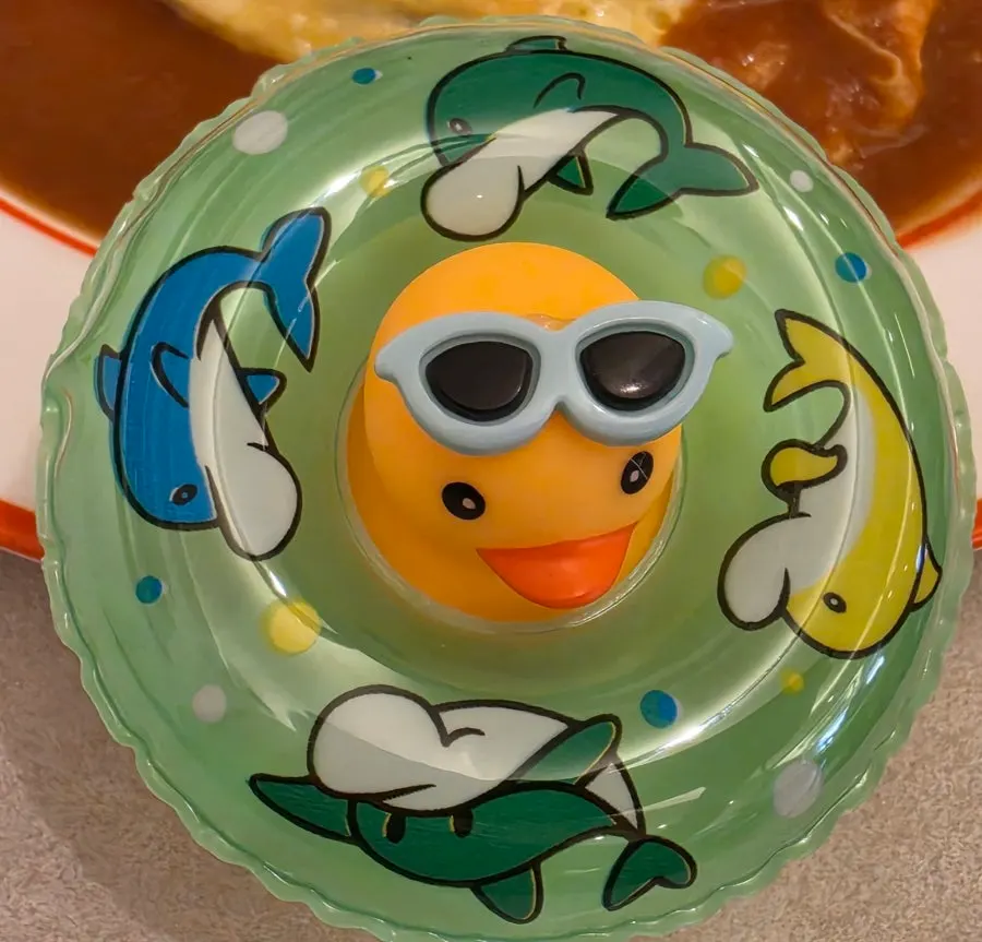 Sunglasses-wearing rubber-duck figure beside a drink