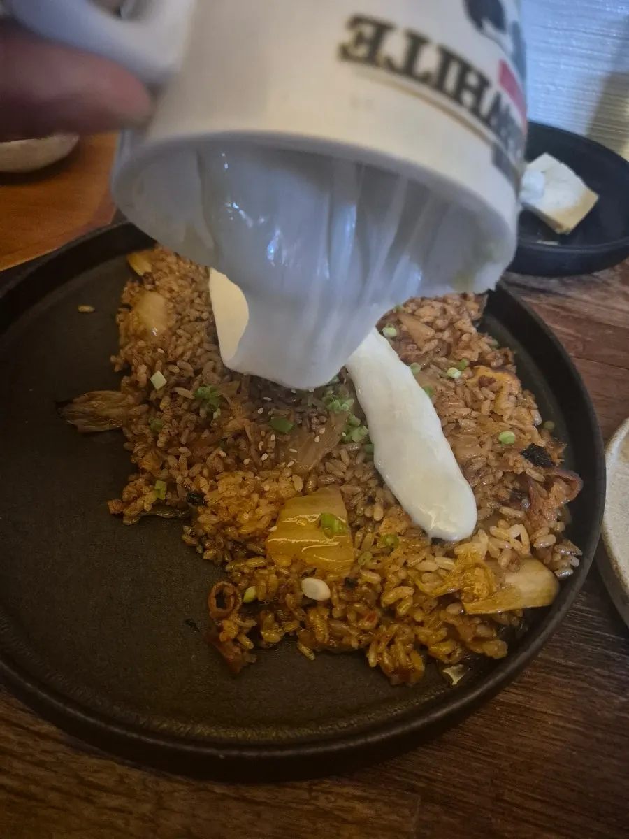 A spoonful of beef belly kimchi fried rice topped with cheese