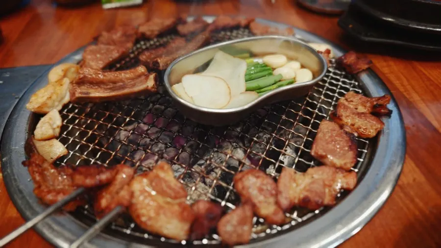 Staff member grilling meat on a charcoal grill as part of the grilling service