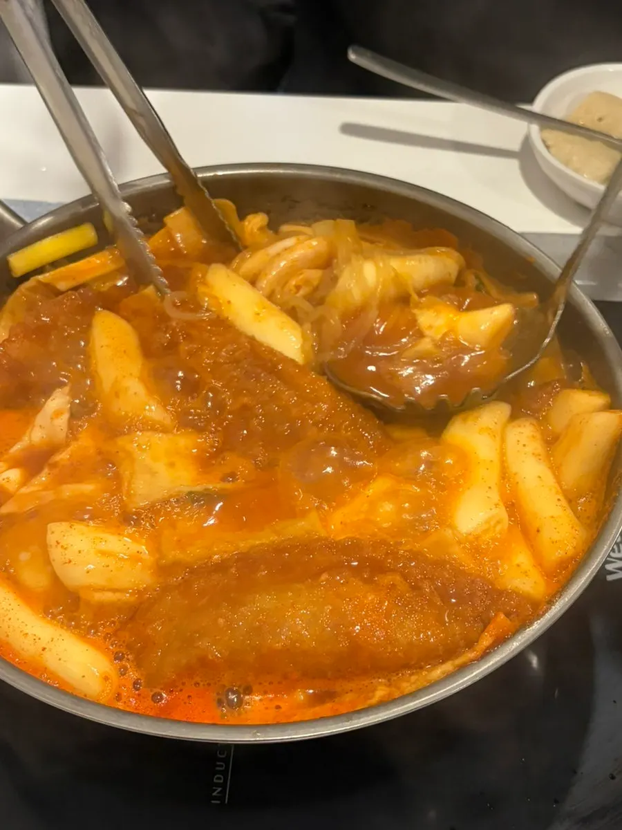 Pot of instant tteokbokki topped with mandu, jjolmyeon, egg and cabbage