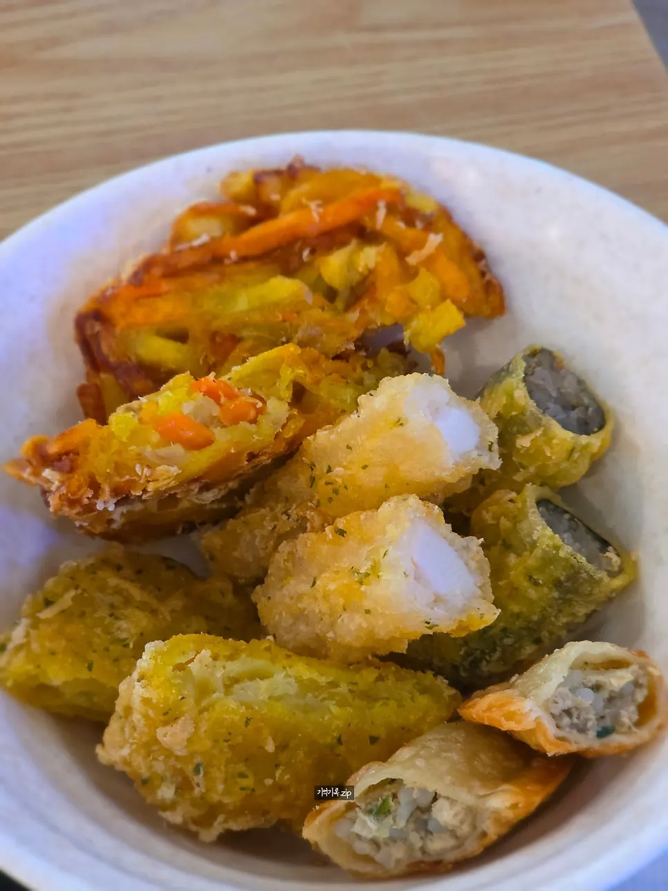 Fritters being dipped into tteokbokki sauce