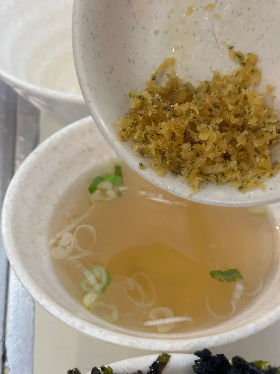 Bowl of fish cake broth topped with fried batter flakes