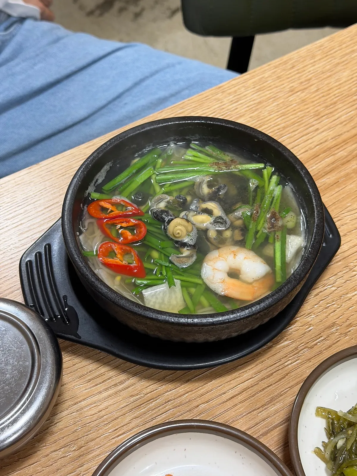 보말해장국 뚝배기와 반찬이 놓인 식탁