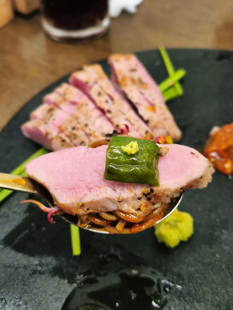 A bite of bibim mak guksu noodles topped with pork tenderloin