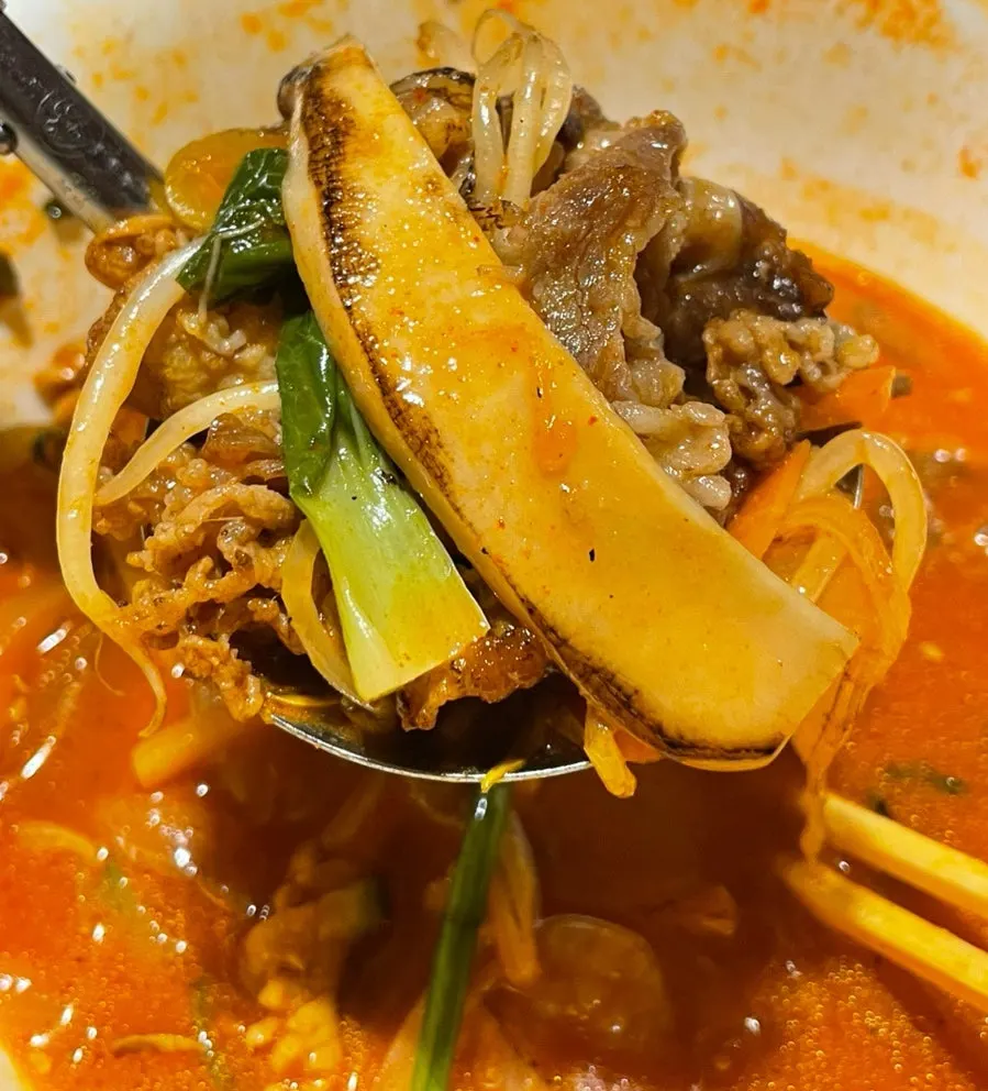 Chewy jjamppong noodles lifted with chopsticks