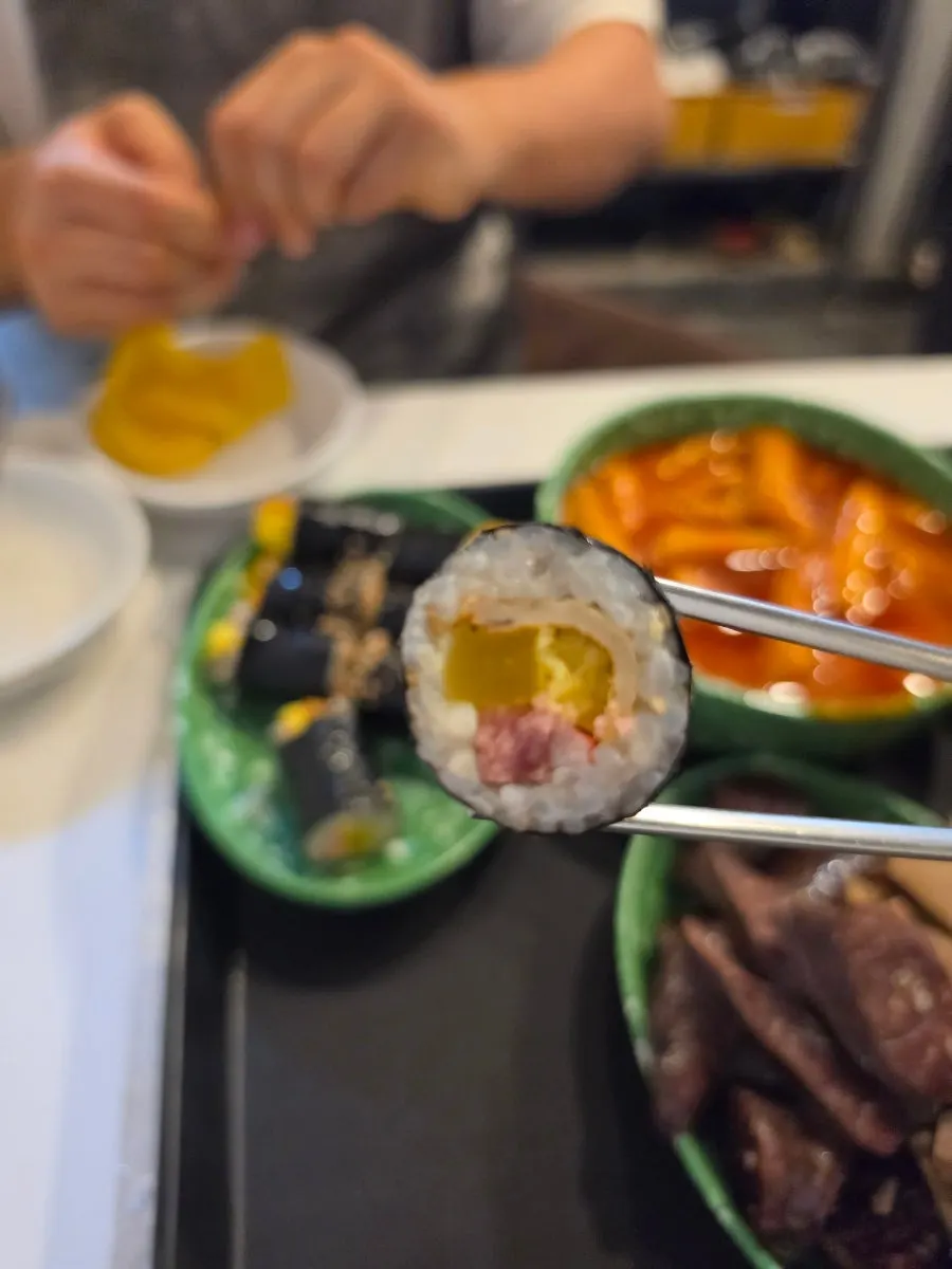Dipping gimbap into the tteokbokki sauce