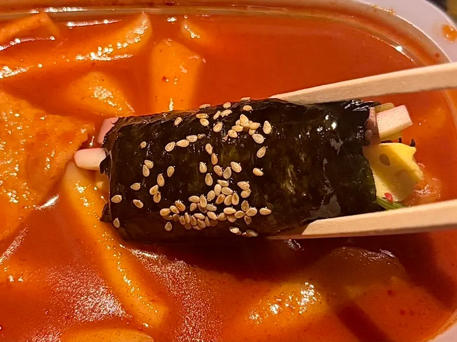 Mini gimbap dipped into tteokbokki sauce