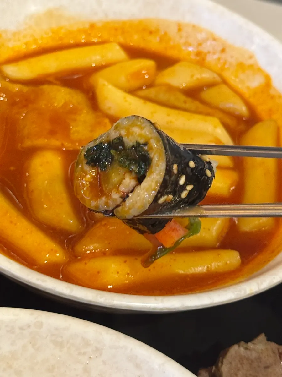 Mini gimbap dipped in tteokbokki sauce