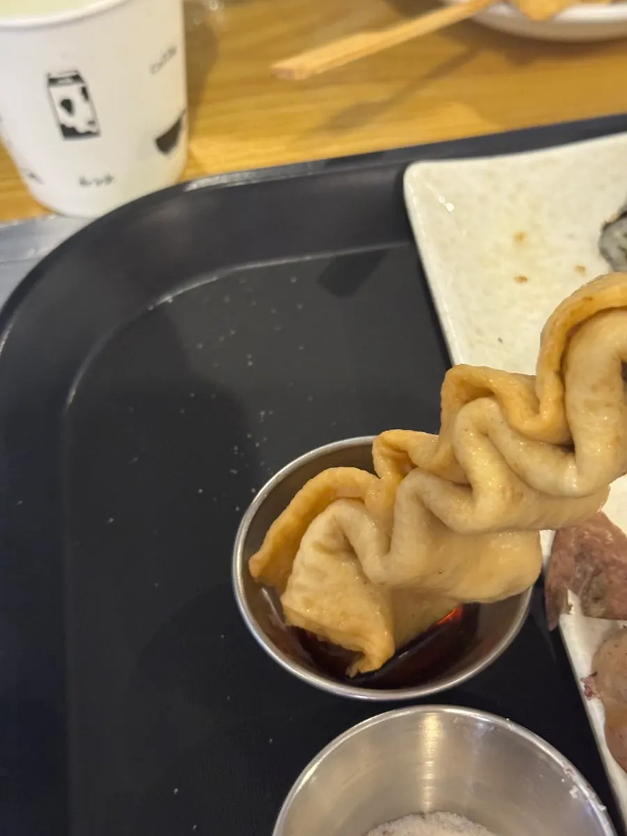 A piece of fish cake dipped in soy sauce