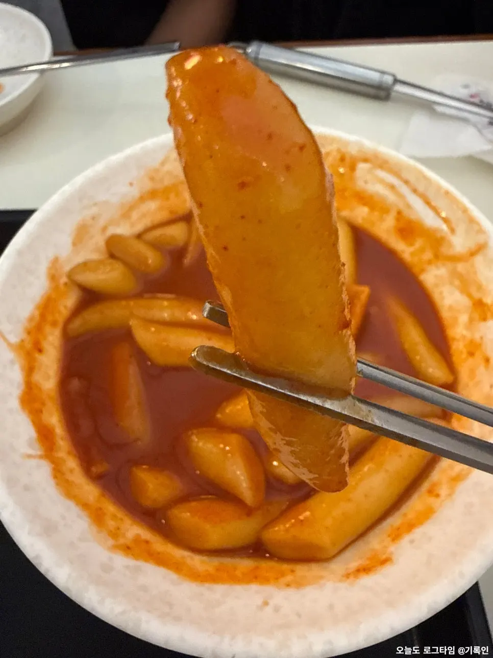 Chewy tteokbokki rice cake lifted with chopsticks