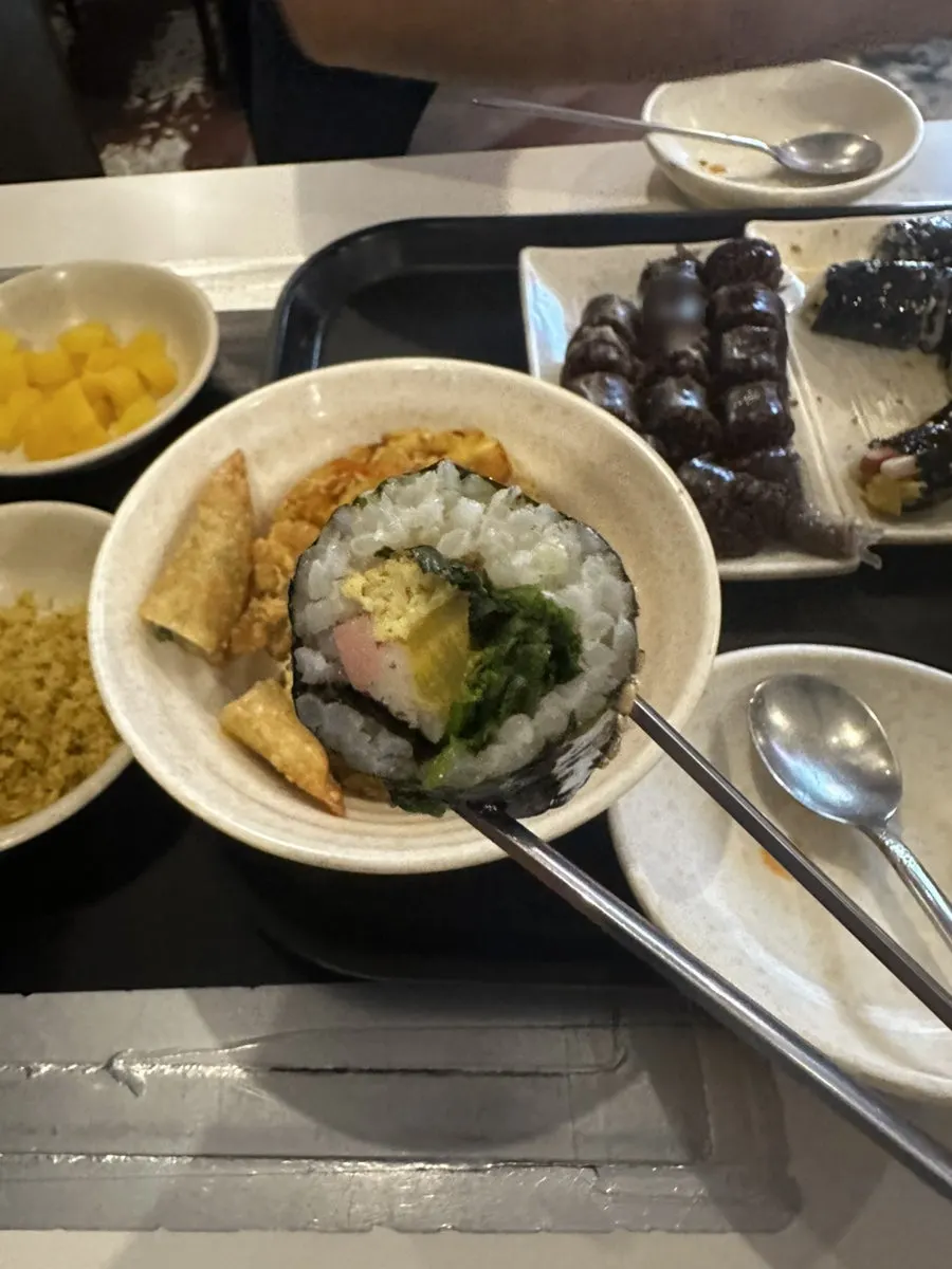 Holding up mini gimbap and a piece of sundae