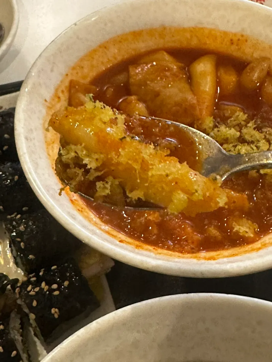 A piece of tteokbokki coated in fry batter powder