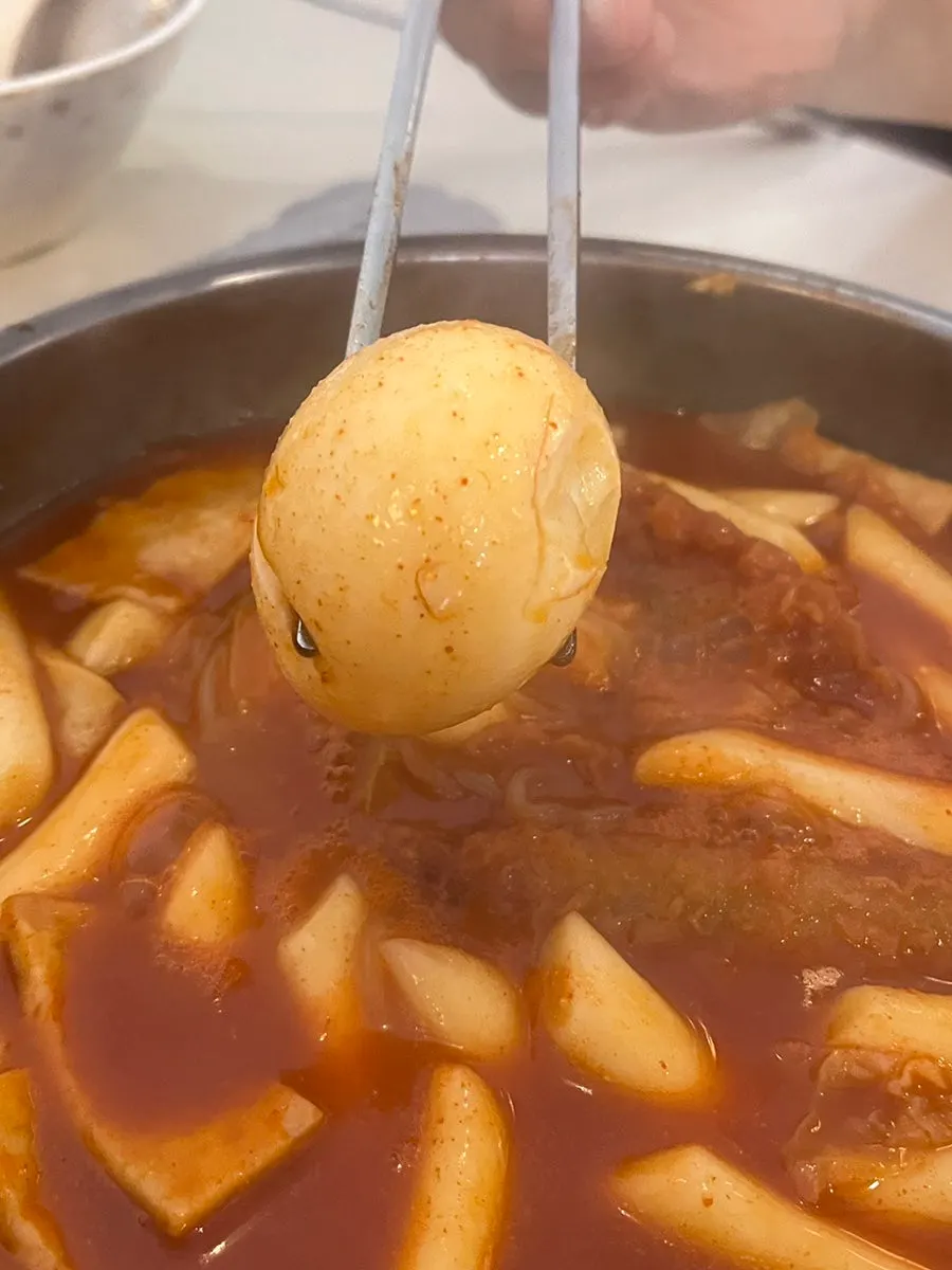 A spoonful of tteokbokki soaked with fried batter bits