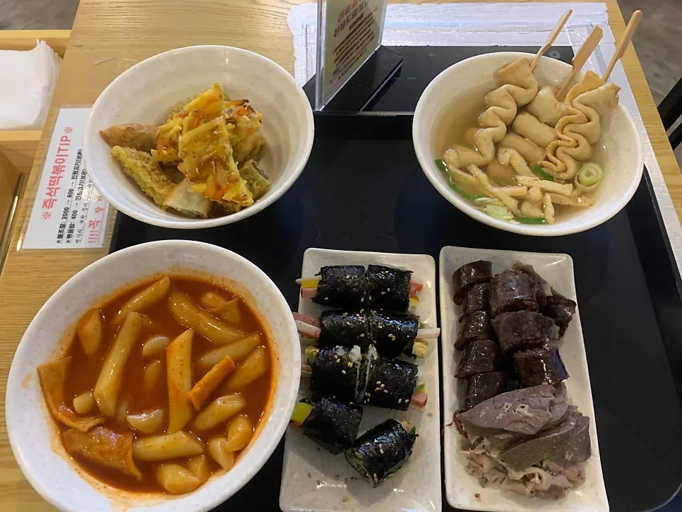 A combo set spread with tteokbokki, gimbap, and fried snacks